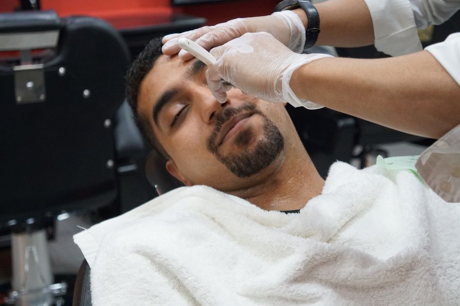 Barber applying hot towel shave prep to a client